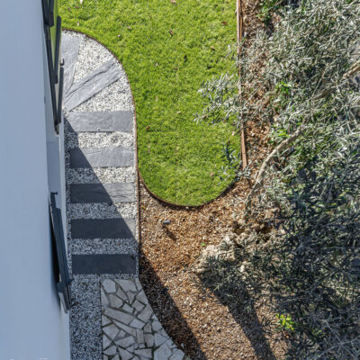 Vue d’une maison contemporaine familiale avec grandes baies vitrées, cuisine ouverte et salle à manger lumineuse donnant sur jardin et piscine.