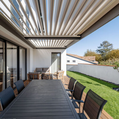 Vue d’une maison contemporaine familiale avec grandes baies vitrées, cuisine ouverte et salle à manger lumineuse donnant sur jardin et piscine.